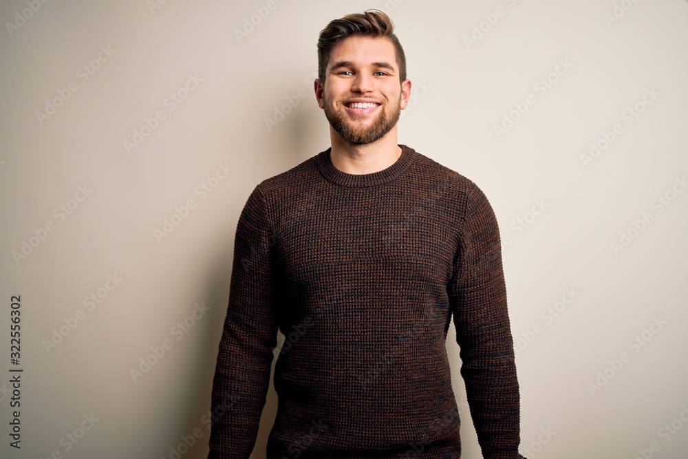 Young handsome blond man with beard and blue eyes wearing casual sweater standing with a happy and cool smile on face. Lucky person.