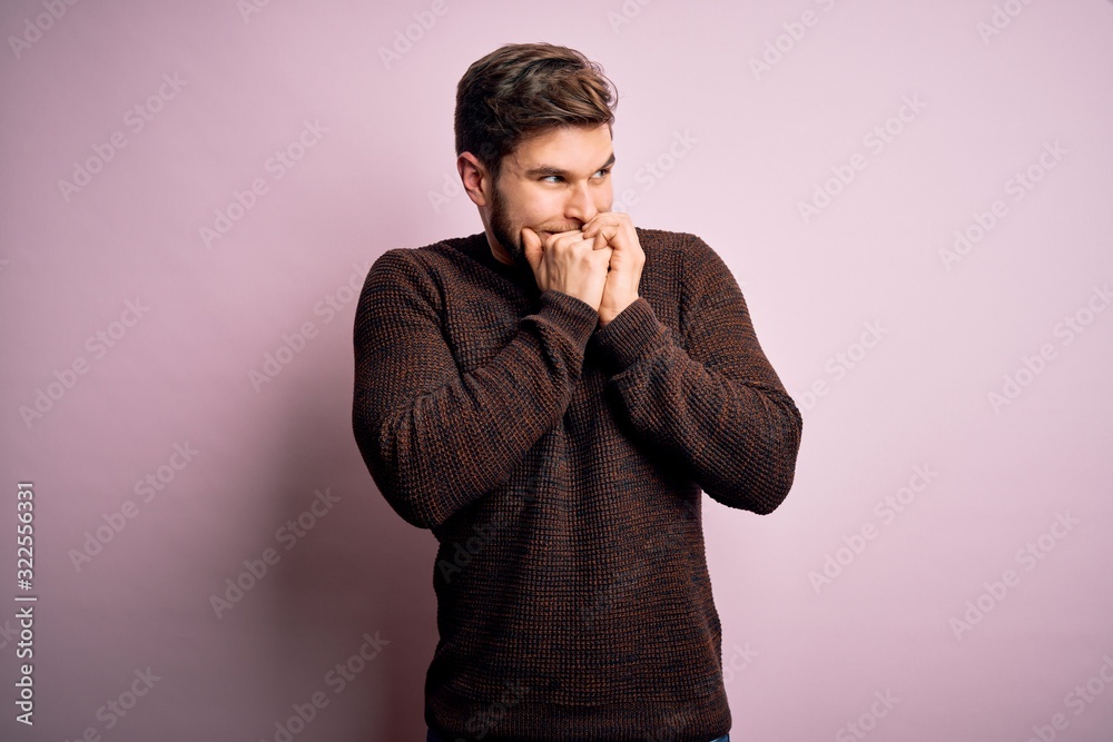 Young blond man with beard and blue eyes wearing casual sweater over pink background laughing nervous and excited with hands on chin looking to the side Young blond man with beard and blue eyes wearing casual sweater over pink background laughing nervous and excited with hands on chin looking to the side