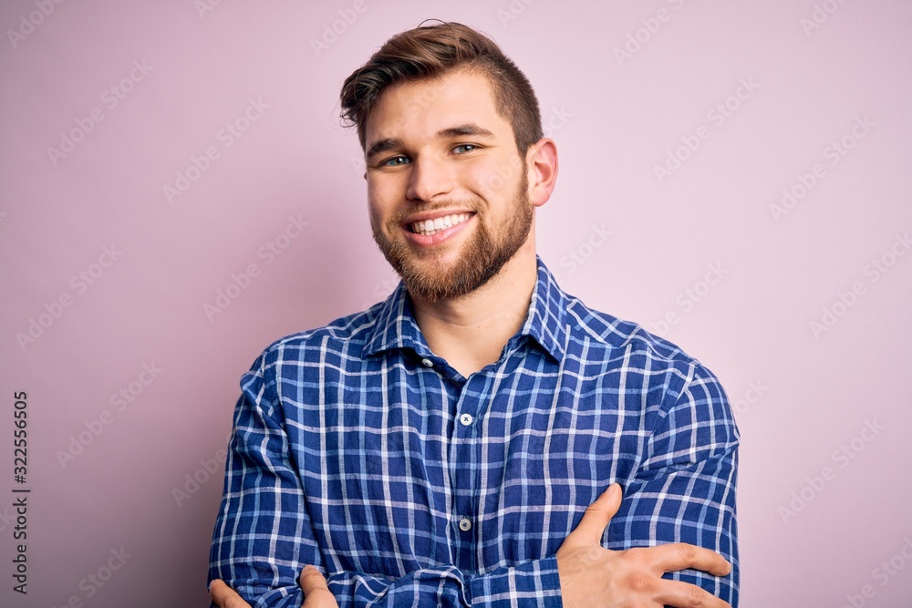 Young handsome blond man with beard and blue eyes wearing casual shirt standing happy face smiling with crossed arms looking at the camera. Positive person. Young handsome blond man with beard and blue eyes wearing casual shirt standing happy face smiling with crossed arms looking at the camera. Positive person.