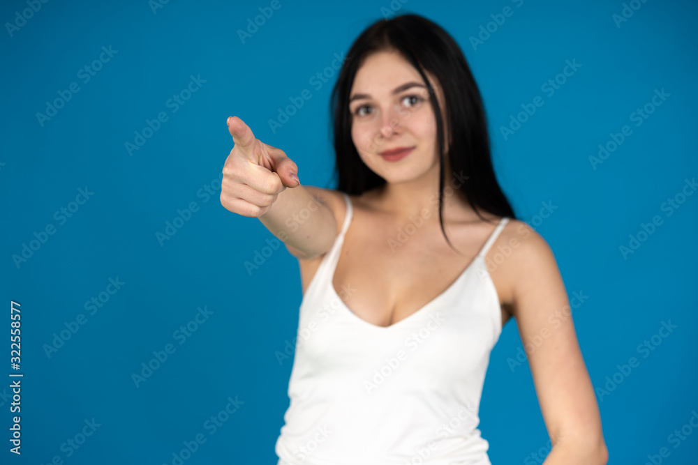 Selective focus of smiling girl pointing with finger to camera isolated on blue background Selective focus of smiling girl pointing with finger to camera isolated on blue background