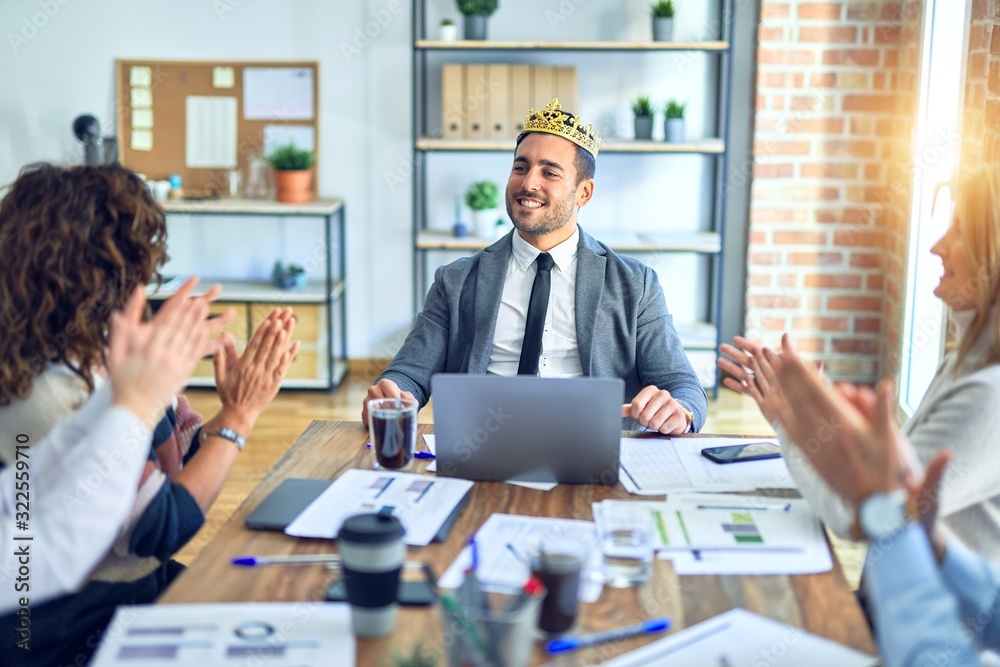 Group of business workers smiling happy and confident. Working together with smile on face applauding one of them wearing king crown at the office Group of business workers smiling happy and confident. Working together with smile on face applauding one of them wearing king crown at the office