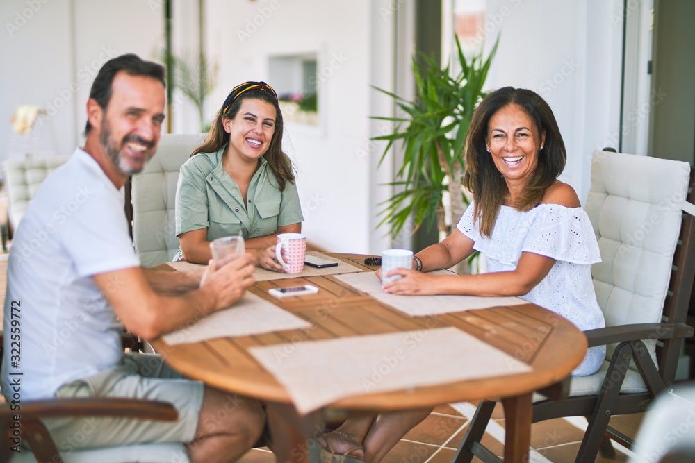 Beautiful family sitting on terrace drinking cup of coffee speaking and smiling Beautiful family sitting on terrace drinking cup of coffee speaking and smiling