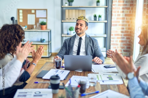 Group of business workers smiling happy and confident. Working together with smile on face applauding one of them wearing king crown at the office