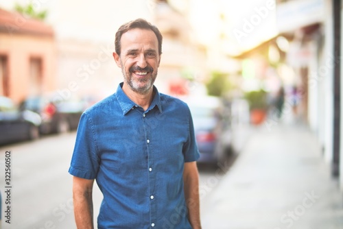 Middle age handsome man standing on the street smiling