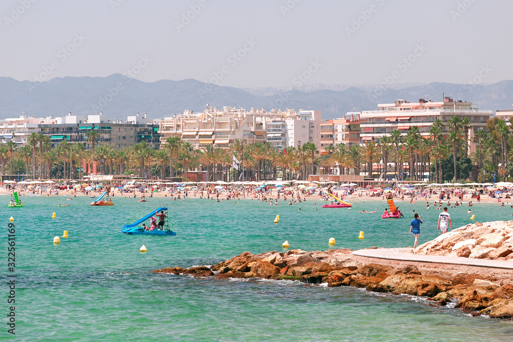 Transparent and turquoise sea, beach with tourists in Salou, Spain.