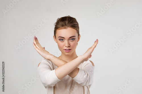 beautiful young woman making stop gesture on gray background. photo