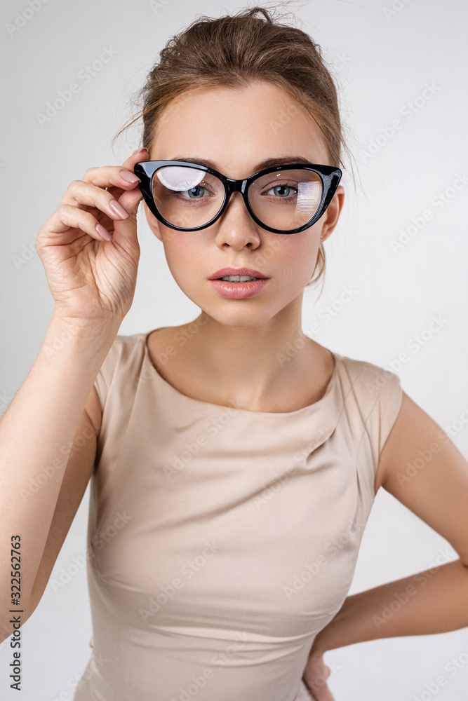 Portrait of smart business woman model in dress wearing glasses and looking at the camera against gray background Portrait of smart business woman model in dress wearing glasses and looking at the camera against gray background