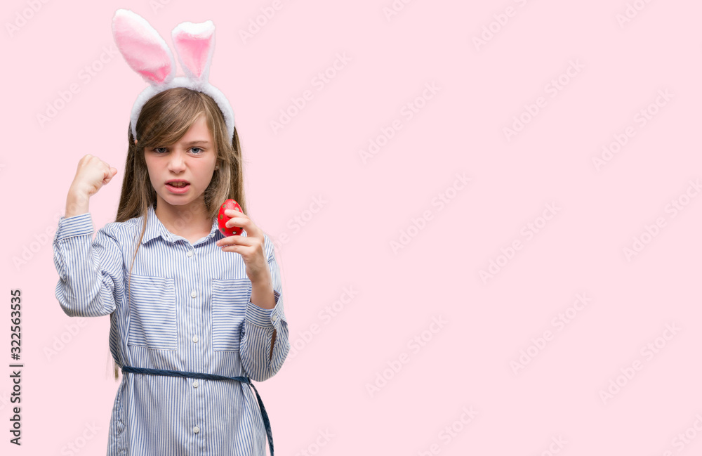 Young blonde child wearing easter bunny ears annoyed and frustrated shouting with anger, crazy and yelling with raised hand, anger concept Young blonde child wearing easter bunny ears annoyed and frustrated shouting with anger, crazy and yelling with raised hand, anger concept