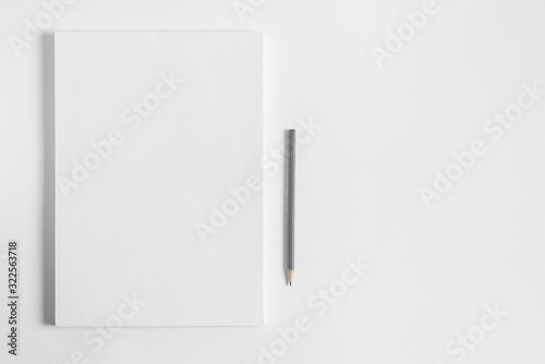 Blank sheets of paper and pencil on white background. Artist workplace. White paper stack with copy space.  Art school template for advertising.