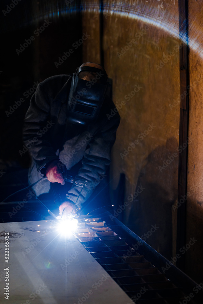 worker in protective uniform and mask welding metal. man using electric welding machine worker in protective uniform and mask welding metal. man using electric welding machine