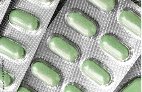 Several of blisters with colored green tablets close-up