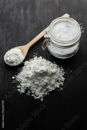 Close-up of tapioca starch or flour powder in wooden spoon with wooden background