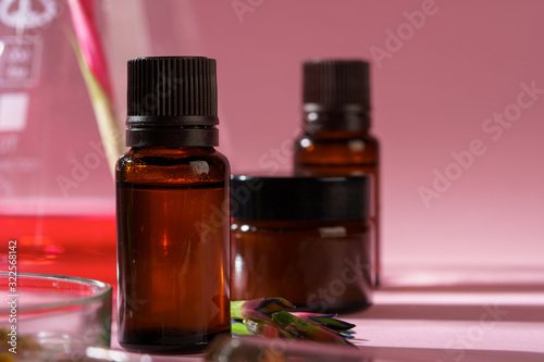 Health, skin care and beauty concept. Cosmetic containers on pink background with plant leaves