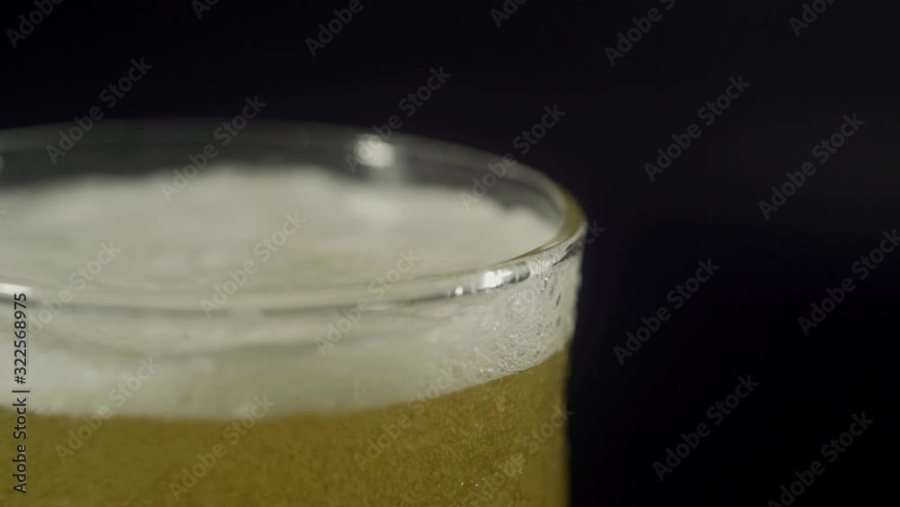 Light foam beer is poured into a transparent glass