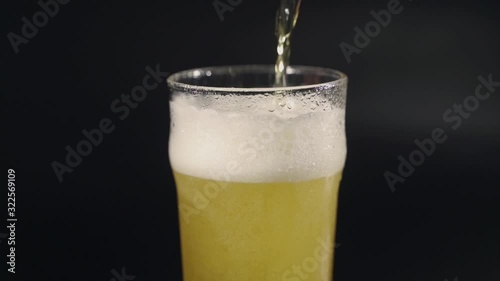 Light foam beer is poured into a transparent glass