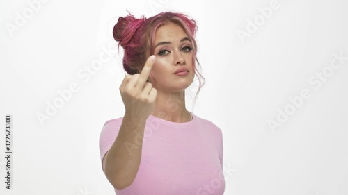 A cocky young woman with the colored pink hairstyle is showing fucking gesture isolated over white background