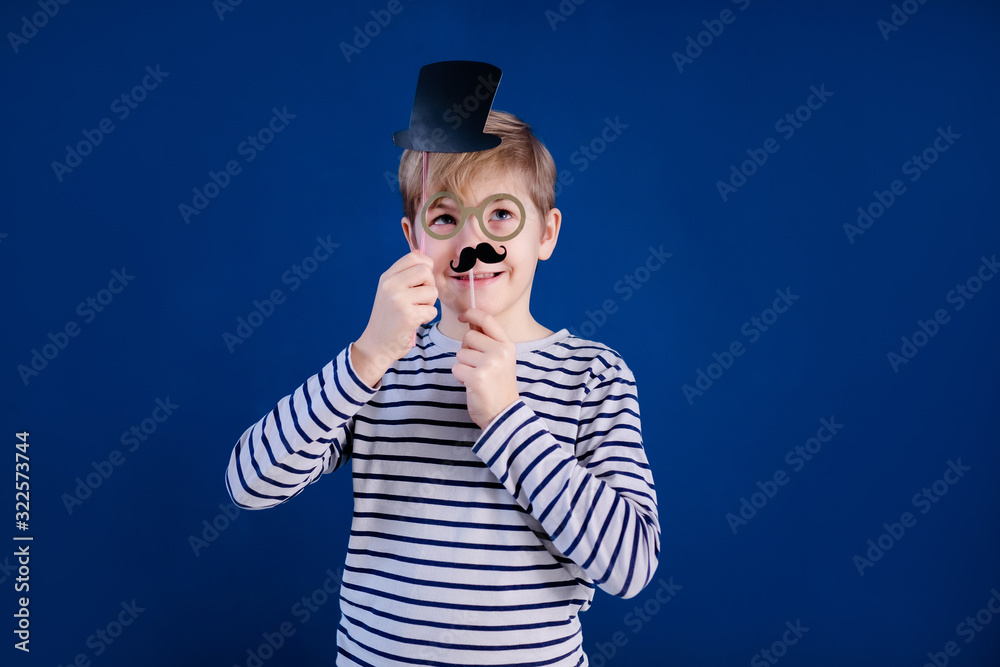 Birthday party and young boy with glasses in hats and props on blue background Birthday party and young boy with glasses in hats and props on blue background