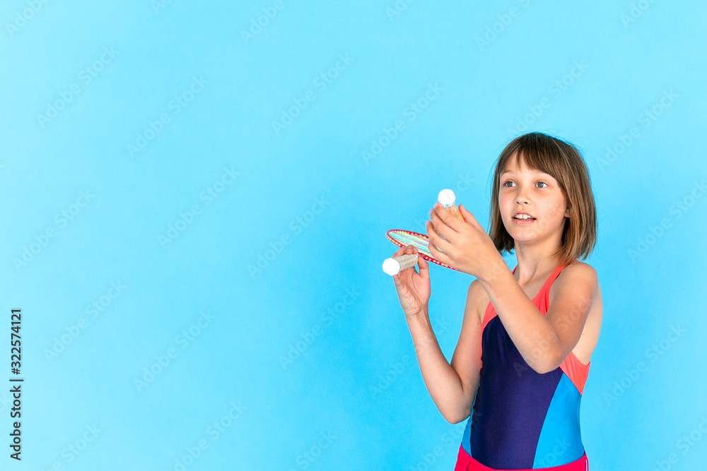Young teenager girl jumping and playing badminton on blue background Young teenager girl jumping and playing badminton on blue background