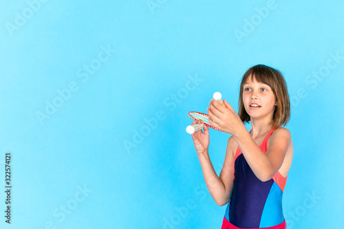 Young teenager girl jumping and playing badminton on blue background