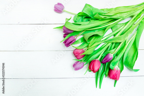 Bunch of red and purple tulips on white wooden background with copy space like postcard on womens day