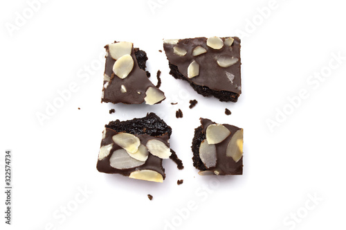 Chocolate brownie with sliced almond nuts toppings broken and crumbs isolated on white background.