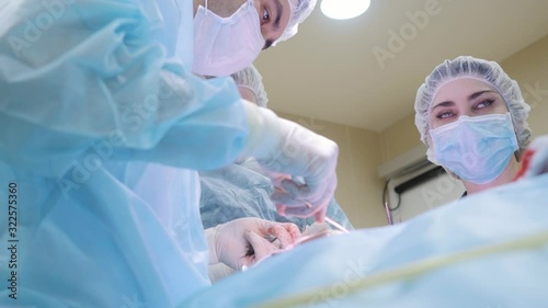 Two surgeons and an assistant perform surgery on the face. Sew a cut. View from below. Medicine, clinic
