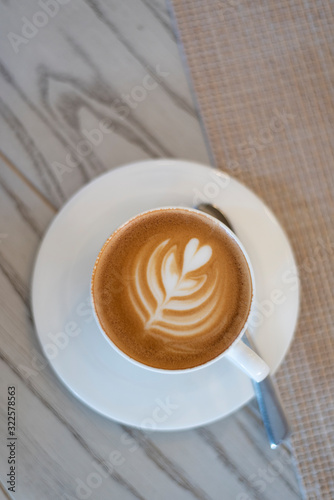 Fresh coffee latte with milk foam drawed heart tree shape art. Caffeine additcition.