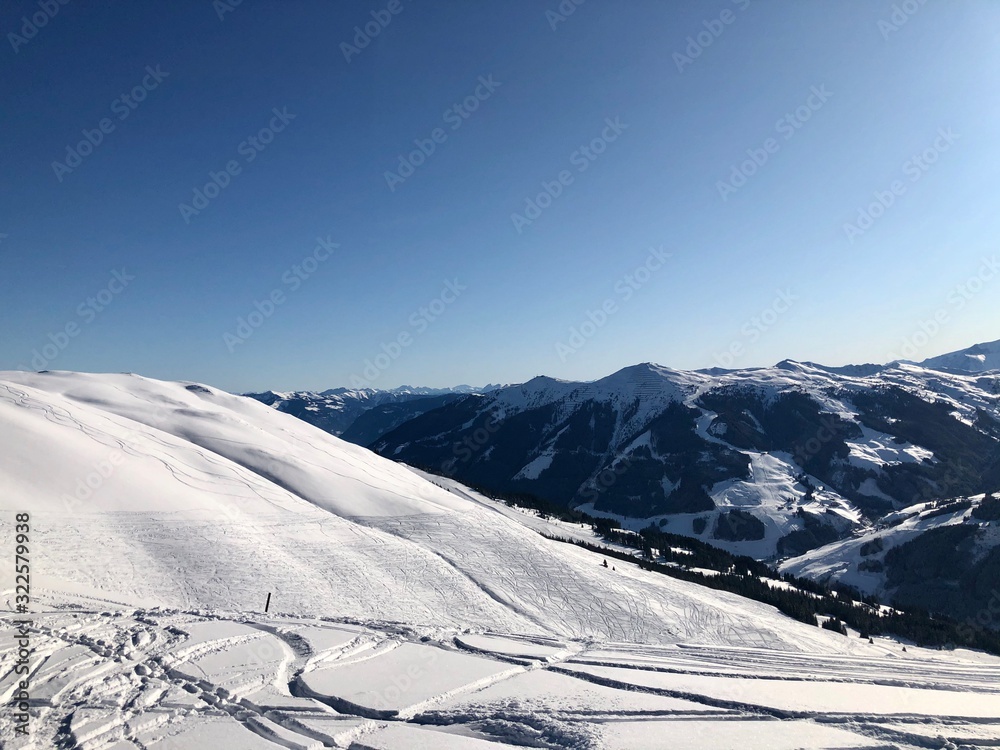 Empty snowy skiing slopes in the mountains with blue sky in Saalbach-Hinterglemm, Austria