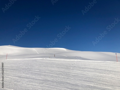 Empty snowy skiing slope in the mountains with blue sky