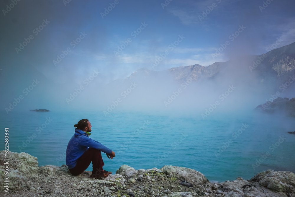 Traveler on the crater lake of Ijen volcano