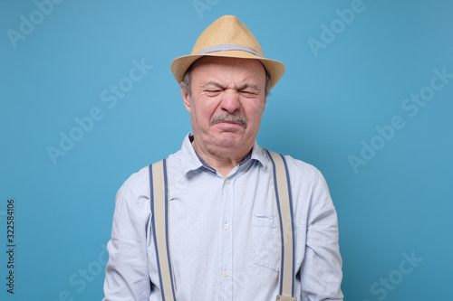 Bild auf Leinwand Senior man in summer hat with disgusted expression repulsing something