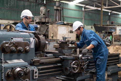 Industrial engineers in safety uniforms wearing white safety helmets are inspecting work by tools.  and on the job training he works in industrial machinery.