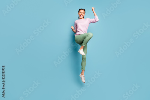 Hooray. Full body photo of funny lady jumping high good mood win sportive competition championship wear casual pink pullover green trousers shoes isolated blue color background photo