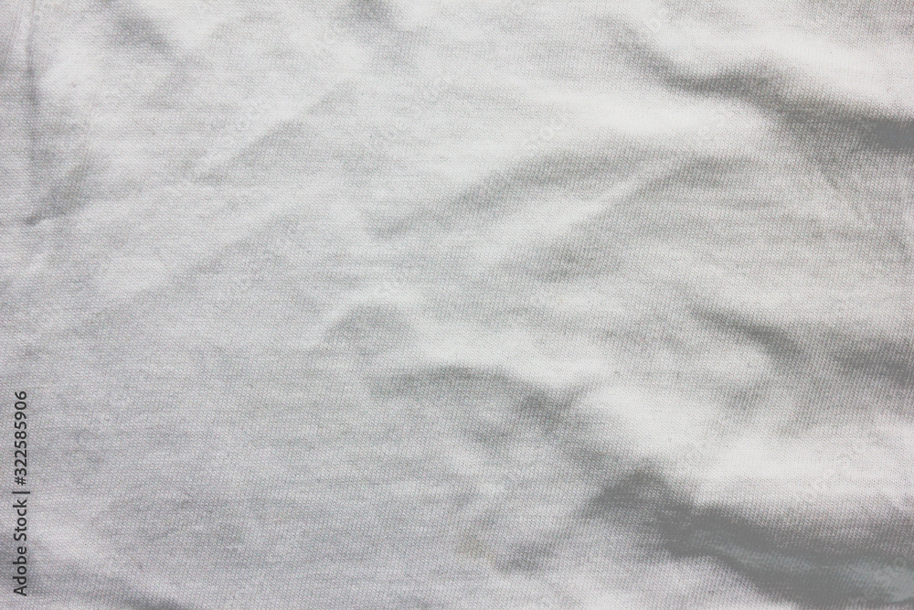 Crumpled white cloth texture, used fabric sheet background. Cotton material  surface, grunge light grey clothing pattern. Wrinkle on elegant shirt for men and women, blanket or sheet, close up