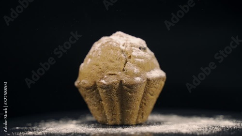 Cupcake with icing sugar on a black background