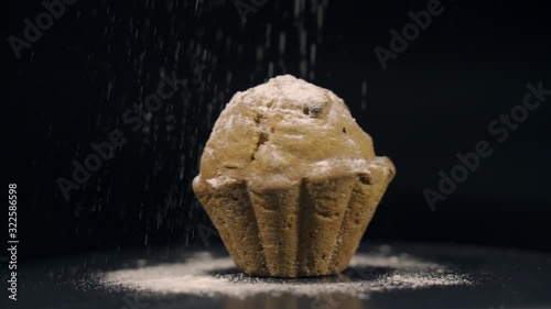 Cupcake with icing sugar on a black background