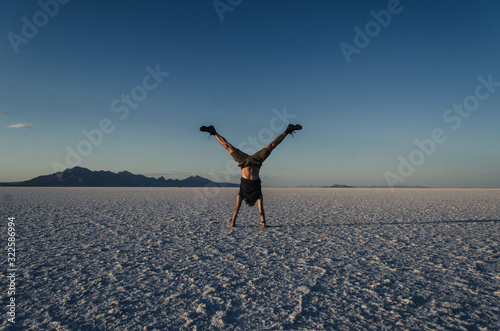 Chłopak stoi na rękach na białej, słonej pustyni