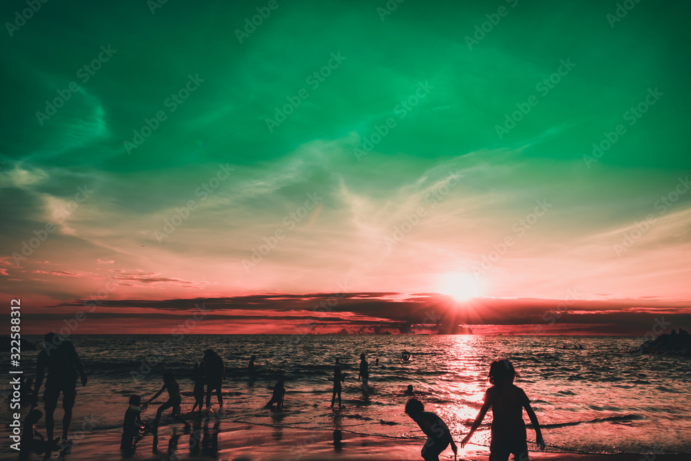 Fototapeta premium Dramatic sky and clouds on the beach at sunset. Silhouettes of people on the beach at sunset. City residents are enjoying a weekend by the sea. 