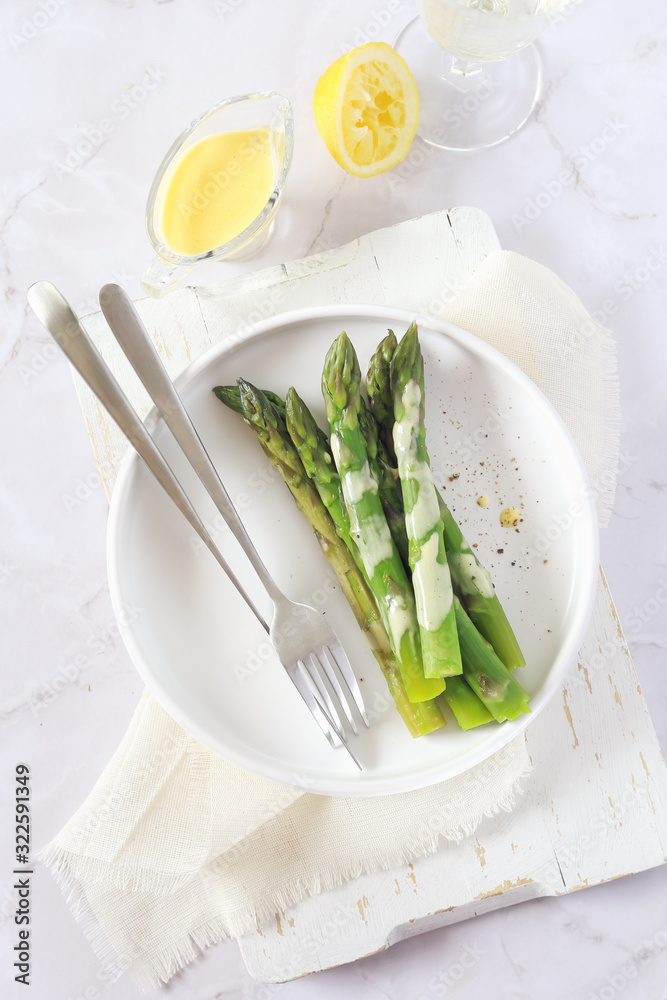 French cuisine. Fresh green asparagus with hollandaise sauce and glass of white wine French cuisine. Fresh green asparagus with hollandaise sauce and glass of white wine