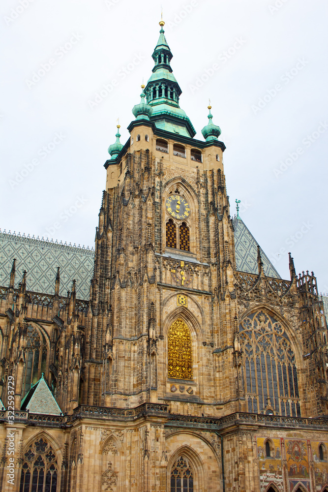 Prague. 05.10.2019: Perspective view of the Metropolitan Cathedral of Saints Vitus, Wenceslaus and Adalbert, an excellent example of Gothic architecture. Golden Gate South Tower with clock.