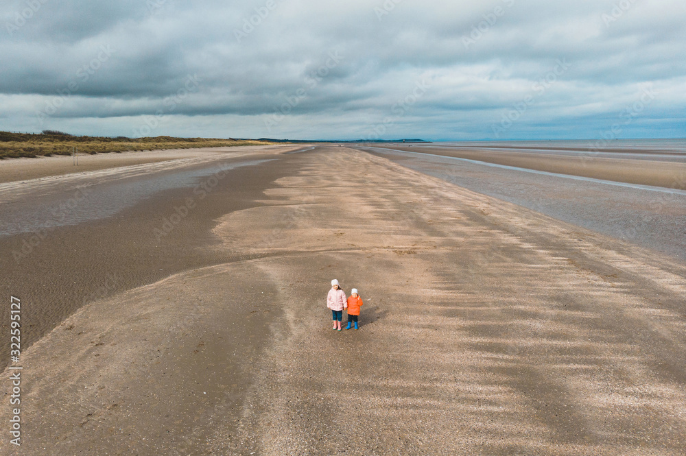 brother and sister holding hands on beach