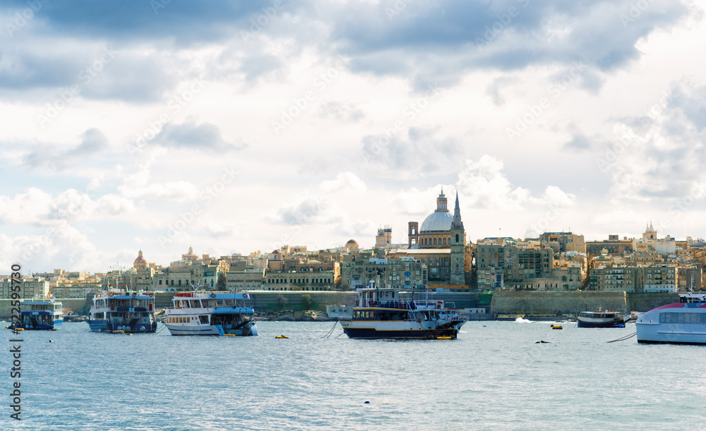 Boats in harbor of Valletta, capital of Malta. Scenic view of maltese coast with ships and traditional houses. Popular famous travel tourism destination island Malta. Sea landscape.