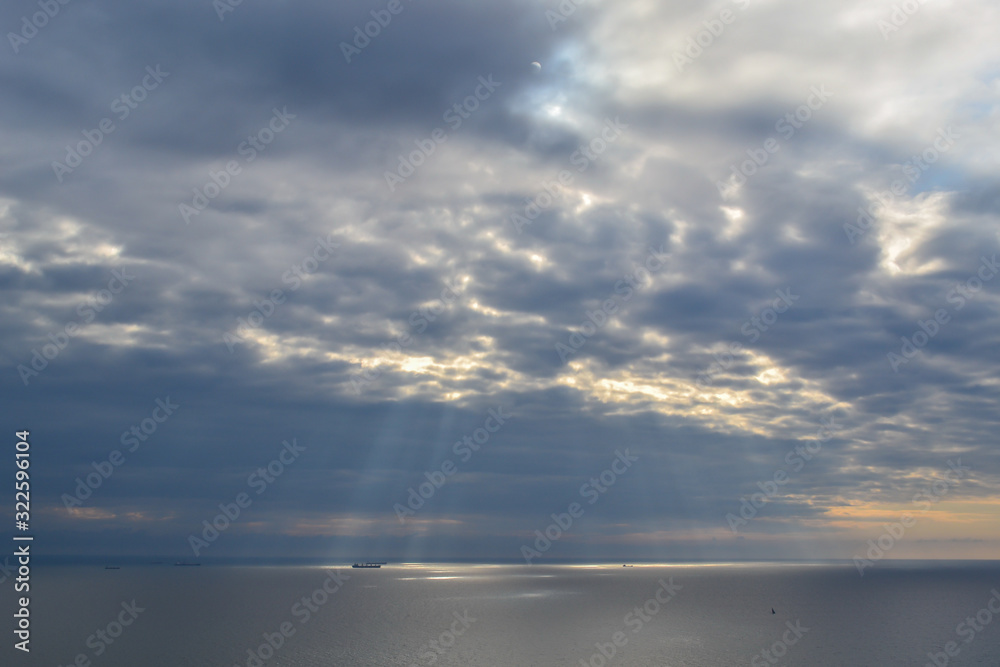 sea, ships, cloudy sky at sunset, the bright rays of the sun