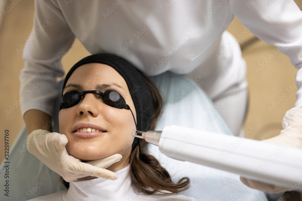 Cosmetologist in white gloves applying make up for woman in beauty salon. Laser peeling of a face. Skin care. Fashion, beauty, makeup, cosmetics, health, spa, wellness. Cosmetologist in white gloves applying make up for woman in beauty salon. Laser peeling of a face. Skin care. Fashion, beauty, makeup, cosmetics, health, spa, wellness.