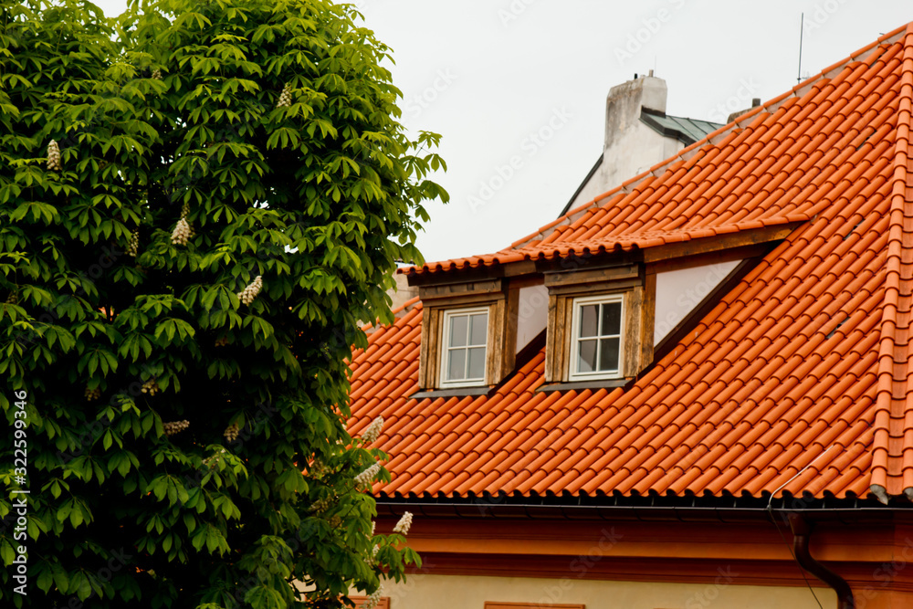 Prague. 05.10.2019: Low light detail of patina red roof top. Prague Lesser Town typical roofing material. Old roofing of clay tiles. Various orange shades and stains.
