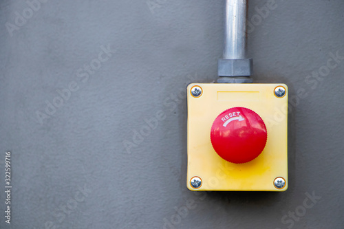 Red Reset button on the wall. red emergency stop switch button in a factory building.