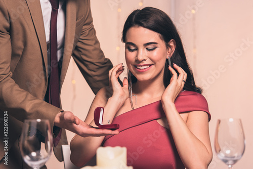 cropped view of elegant man making marriage proposal to happy girlfriend in restaurant
