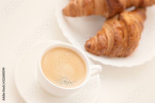 Croissants on a white plate and a cup of coffee. Breakfast is delicious and healthy.