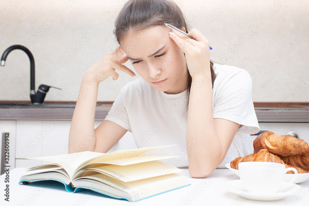 Young woman carefully reads a book, thinks, focused Young woman carefully reads a book, thinks, focused