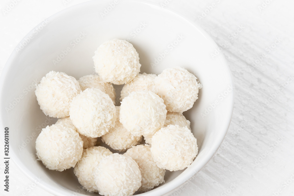 White sweets with coconut, nuts and cream in a plate on a white background closeup White sweets with coconut, nuts and cream in a plate on a white background closeup